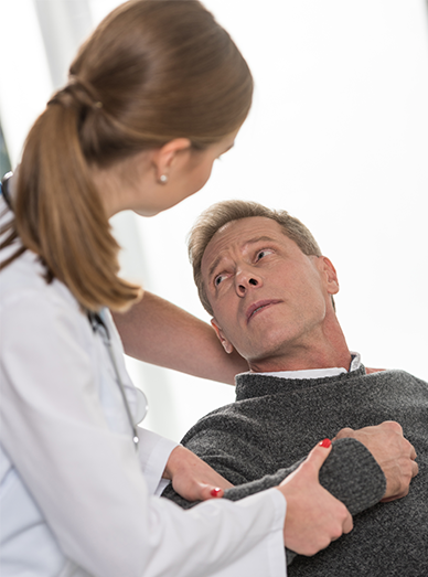 Doctor assisting a middle-aged man during examination for acute or chronic conditions at Windmill Practice.