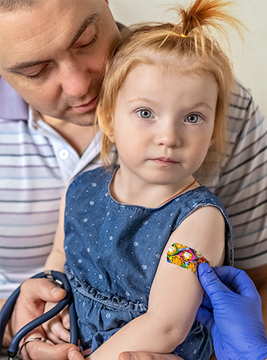 Child with a parent receiving a vaccine and wearing a colourful bandage on the arm at Windmill Practice.