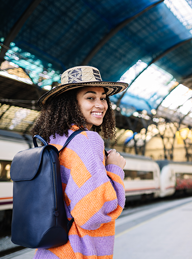 Young traveler with a backpack at a train station, illustrating travel health advice and vaccinations at Windmill Practice.