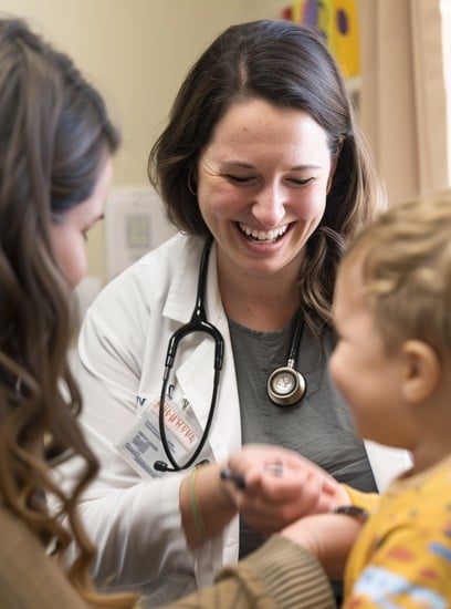 Smiling female doctor interacting with a young child during a family health visit at Windmill Practice.